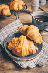 Coffee and croissant on rustic wooden table. French breakfast. Top view. Flat lay. Copy space.