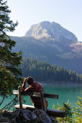 girl sitting on a bench by the lake and looking at the mountain
