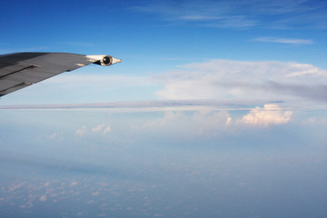 Aircraft Wing on the beautiful heaven and destination of journey on blue sky and cloud in sunlight