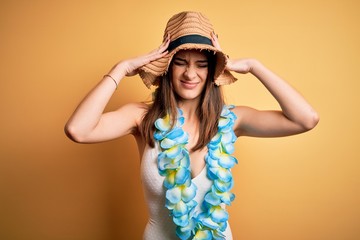 Naklejka premium Young beautiful brunette woman on vacation wearing swimsuit and Hawaiian flowers lei suffering from headache desperate and stressed because pain and migraine. Hands on head.