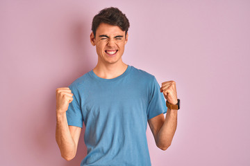 Teenager boy wearing casual t-shirt standing over blue isolated background very happy and excited...