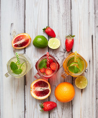 Summer drinks. Fresh freshes on a wooden background. View from above. Orange, lemon and strawberry fresh.