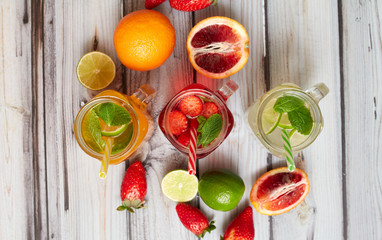 Summer drinks. Fresh freshes on a wooden background. View from above. Orange, lemon and strawberry fresh.