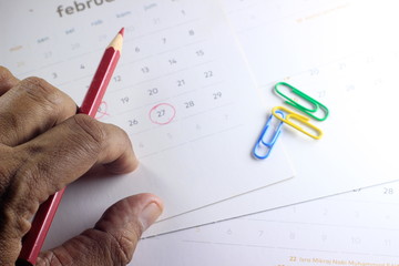 Simple Top View Close Up Photo Illustration, Re-Schedule Marked by man Hand with Red Color Pencil, Focus to Date at calendar