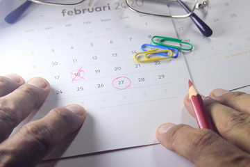 Simple Top View Close Up Photo Illustration, Re-Schedule Marked by man Hand with Red Color Pencil, Focus to Date at calendar