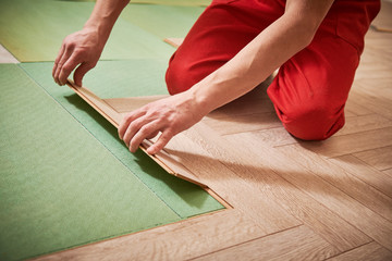worker laying laminate floor covering at home renovation