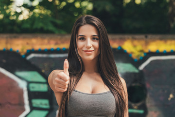 trendy beautiful long haired model posing on graffiti background and show thumb up