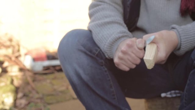 Woman carving a piece of wood with a knife