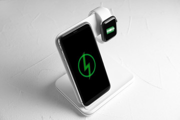 Mobile phone and smartwatch charging with wireless pad on white stone table © New Africa