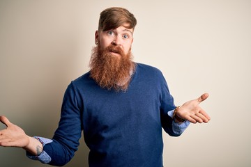 Handsome Irish redhead business man with beard standing over isolated background clueless and...