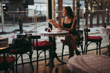 Fototapeta na wymiar Young woman reading book in cafe