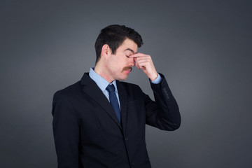 Very upset, charming, nice man touching nose between closed eyes standing outdoors, want to cry, having stressful relationship, worry about conflict with his lover or having troubles with work