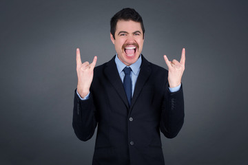 Born to rock this world. Joyful man in fashionable clothes screaming out loud and showing with raised arms horns or rock gesture, expressing excitement of being on concert of band.