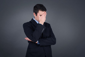 Indoor portrait of handsome man with stylish haircut, wearing casual clothes, making facepalm...
