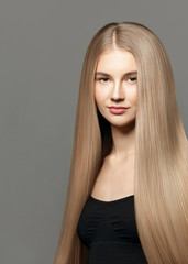 Beauty Blonde  model. Beautiful young woman with long healthy hair posing against grey background. Beauty salon concept
