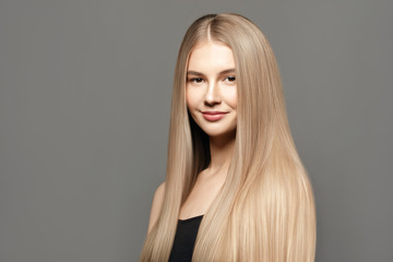 Beautiful young woman with long healthy hair posing against grey background. Beauty salon concept