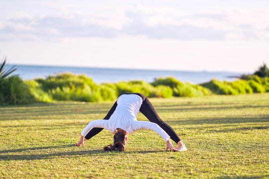 Young beautiful sportwoman practicing yoga. Coach teaching postures at park