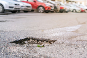 pothole with water after rain on asphalt roadway