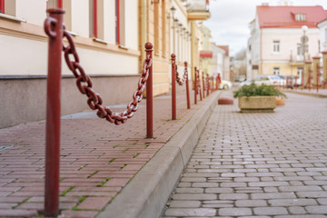 pedestrian area at city street with red metal pole with chain