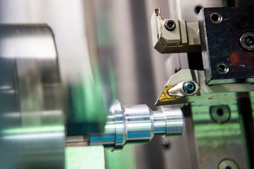 The CNC lathe machine in metal working process cutting thread the metal shaft parts with in the light blue scene. The hi-technology metal working processing by CNC turning machine .