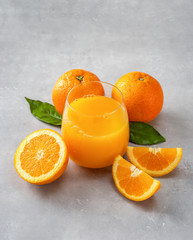 Top view of fresh orange juice, oranges and slices on blue background
