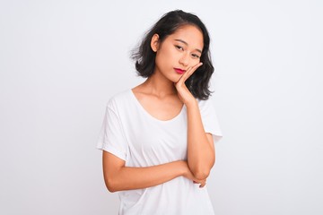 Fototapeta premium Young chinese woman wearing casual t-shirt standing over isolated white background thinking looking tired and bored with depression problems with crossed arms.
