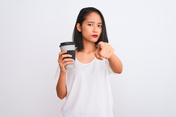 Young chinese woman drinking take away glass of coffee over isolated white background pointing with finger to the camera and to you, hand sign, positive and confident gesture from the front