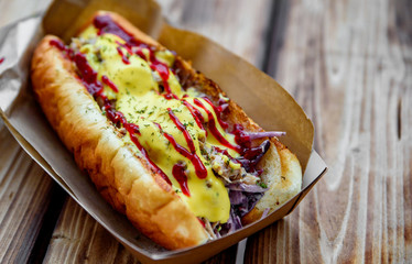 Philly cheese steak sandwich with meat, vegetables, cheese and sause in box on wooden table. street food