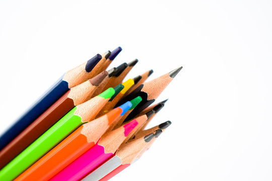Assortment of different colored pencil crayons pointing up on a white background
