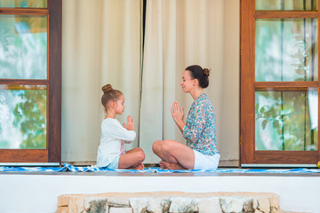 Obraz premium Happy young family meditating on the terrace
