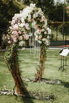 Blooming decoration of wedding arch with roses, hydrangea and eucalyptus. Wedding wood decoration. Wooden board decorated by flowers and greenery and lounge zone. Wedding photo zone rustic style.