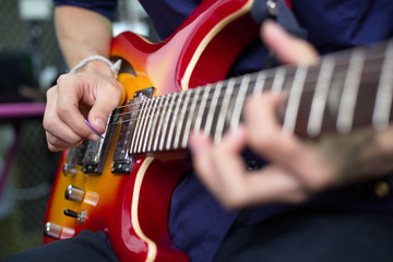 musician's hand is playing a red electric guitar in the recording room.