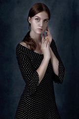 Dramatic portrait of a beautiful lonely girl with blond hair isolated on gray background in studio shot