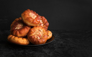 Fried peremyachi, belyashi, pies on a black background. Traditional Russian pies. Russian, Bashkir and Tatar cuisine. Copy space.