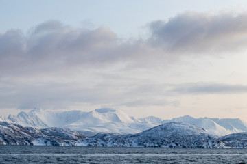 Arctic landscape in winter with snowy mountains and sea. Norwegian coasts and fjords seen from the boat in the open sea. Arctic polar north europe landscape with white snow and ice