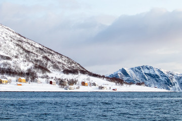 Arctic landscape in winter with snowy mountains and sea. Norwegian coasts and fjords seen from the boat in the open sea. Arctic polar north europe landscape with white snow and ice