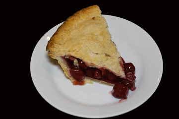 Slice of double crusted cherry pie on black background. Traditionally, cherry pie is made with tart rather than sweet cherries.