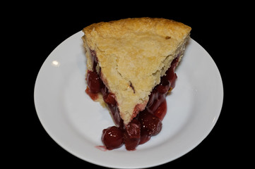 Slice of double crusted cherry pie on black background. Traditionally, cherry pie is made with tart rather than sweet cherries.
