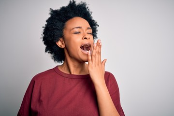 Fototapeta na wymiar Young beautiful African American afro woman with curly hair wearing casual t-shirt standing bored yawning tired covering mouth with hand. Restless and sleepiness.