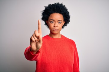 Young beautiful African American afro woman with curly hair wearing red casual sweater Pointing with finger up and angry expression, showing no gesture