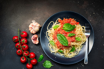 delicious appetizing classic spaghetti pasta, tomato sauce.with basil herbs parmesan cheese on dark background.Space for text. Overhead. Traditional Italian cuisine. Dark rustic wooden table.