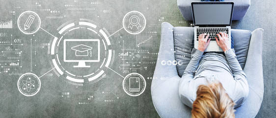 E-learning concept with man using a laptop in a modern gray chair