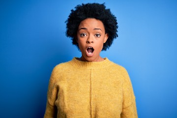 Fototapeta na wymiar Young beautiful African American afro woman with curly hair wearing yellow casual sweater afraid and shocked with surprise and amazed expression, fear and excited face.