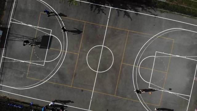 Drone clip of street basketball game outside. 
They are playing Black top. This is warmup for final game of black top.