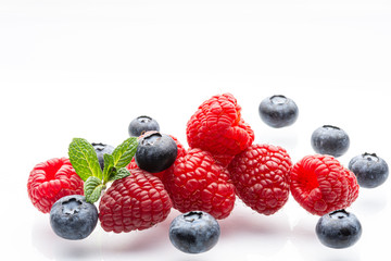Ripe wild berries on a white background. A sprig of fresh mint. Garden raspberries. Ripe blueberries. White background. Red. Blue. Isolated.