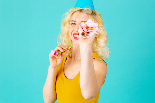 Portrait of a happy, smiling young woman celebrating fun birthday with confetti falling, isolated on blue