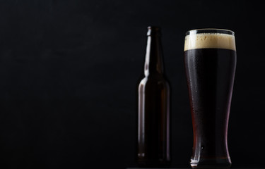 A glass and a bottle of beer on the dark stone table in the bar copy space