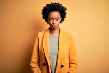 Fototapeta na wymiar Young beautiful African American afro businesswoman with curly hair wearing yellow jacket depressed and worry for distress, crying angry and afraid. Sad expression.