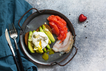 Valentine's day breakfast. Boiled egg sandwich with avocado, coffee, salmon and smoked salmon on a stone concrete tabletop. Top view flat lay background.
