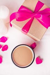 Cup of coffee and a heart shaped lilac sweet candy with gift box on the white table